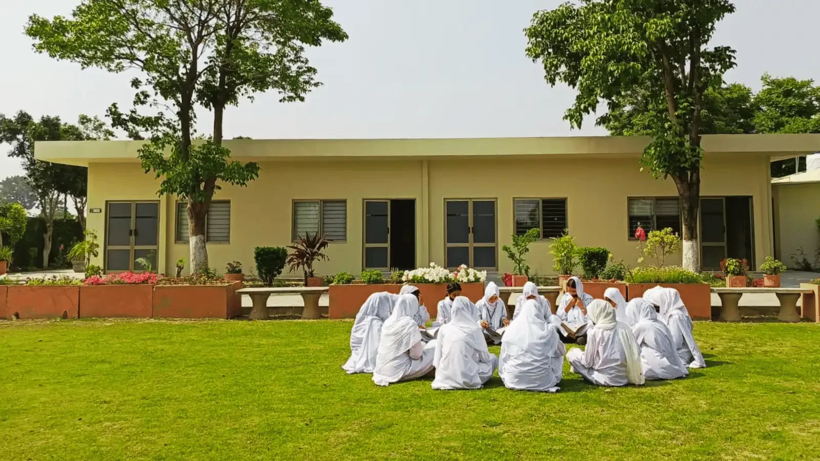 Nursing and midwifery students studying together on the lawn at the Mandra campus