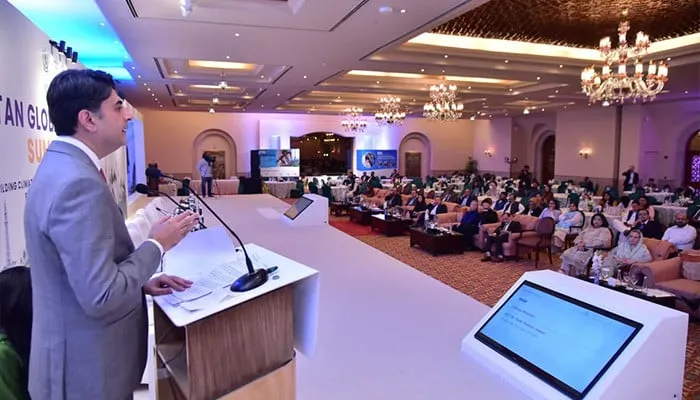 A speaker addresses the summit hall, from The News